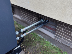 Anschlüsse und Leitungsführung der Luftwärmepumpe durch die Hauswand in den Heizungsraum.